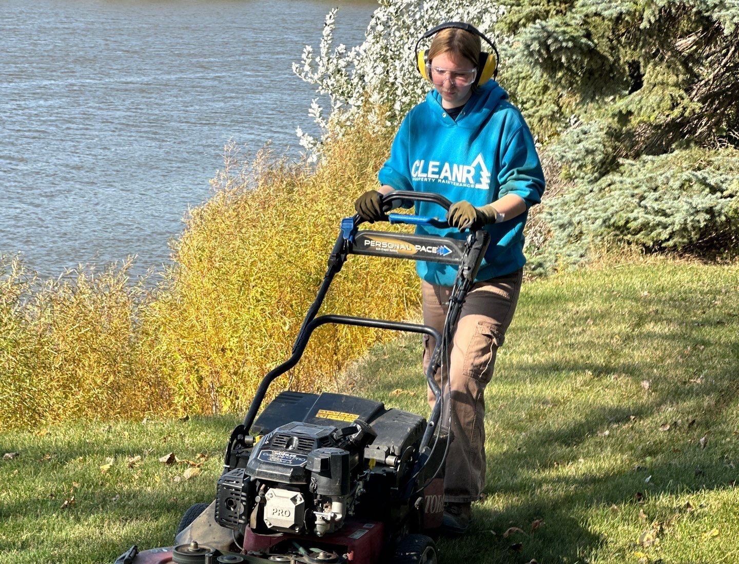 cleanr employee mowing a riverside lawn